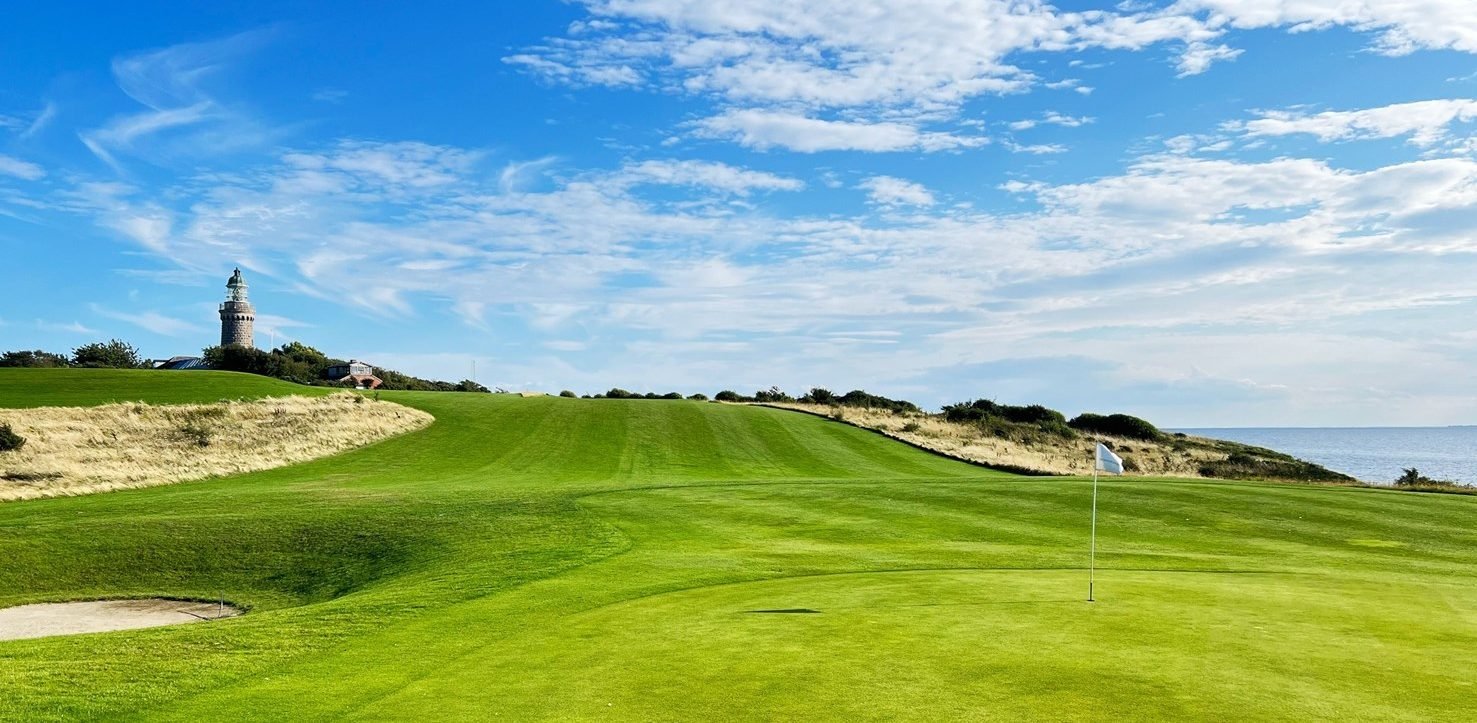 Green at Ærø Golf Klub with a flag and a lighthouse in the background