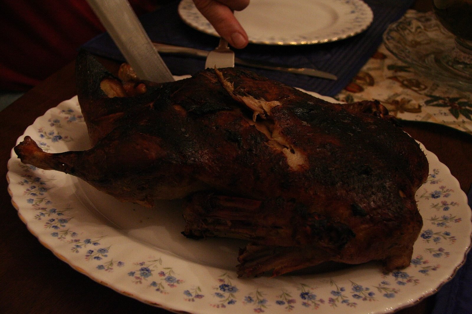 Roast duck on a serving platter being carved at the Christmas table